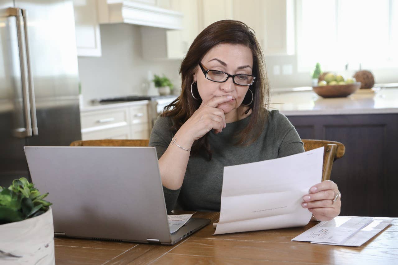 Woman using laptop and reviewing bill