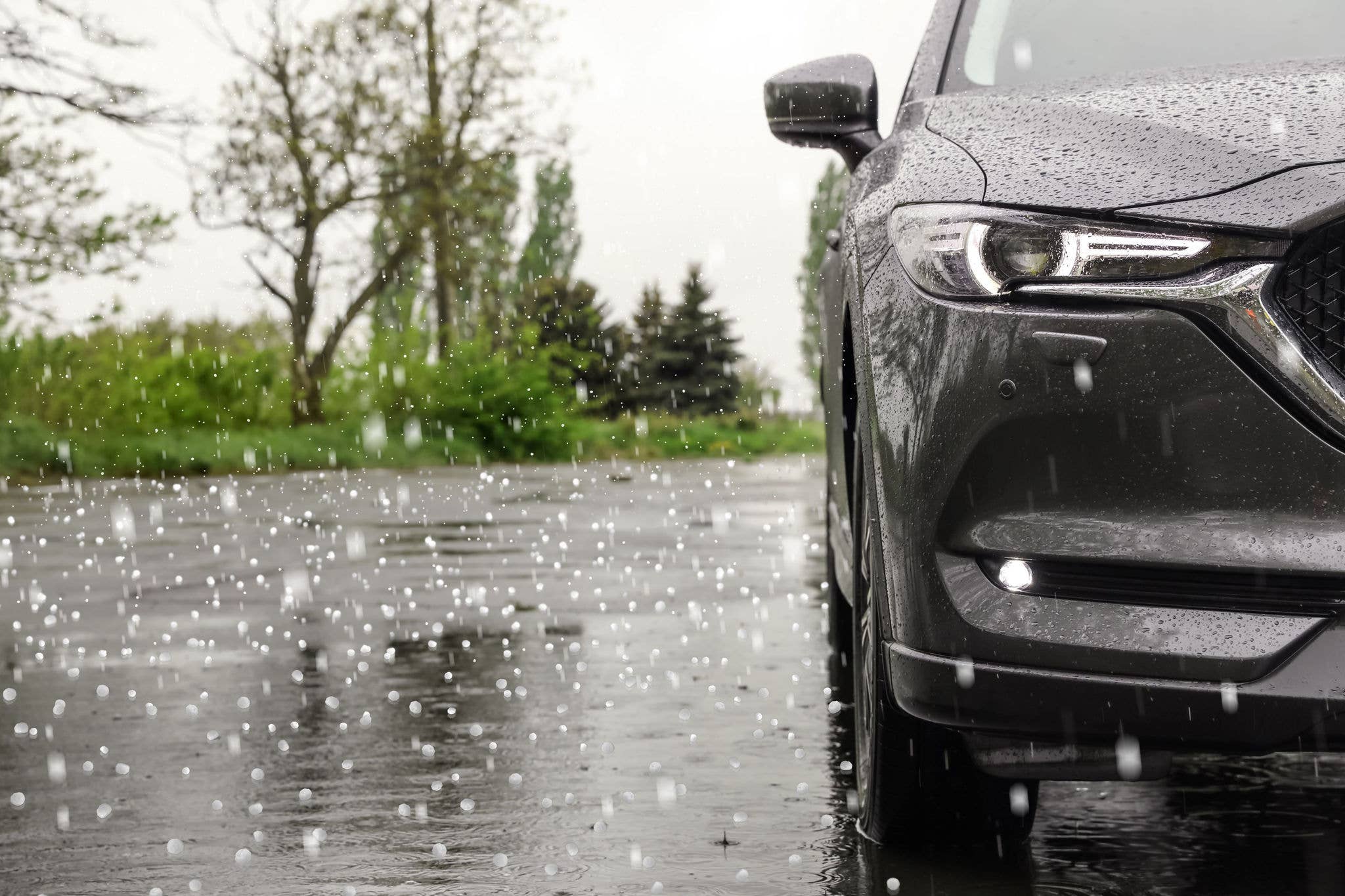 Gray car in driveway getting hailed on